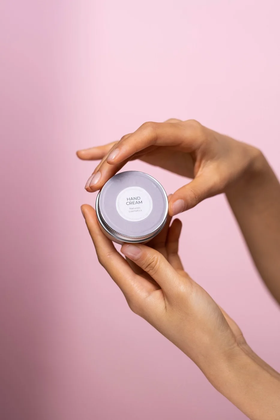 A hand holding a jar of cream