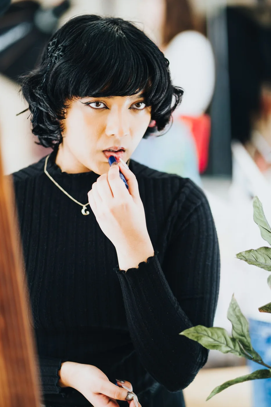 Woman applying a bold lipstick in front of a mirror