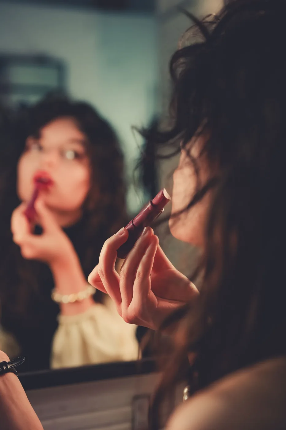Woman applying lipstick in her mirror