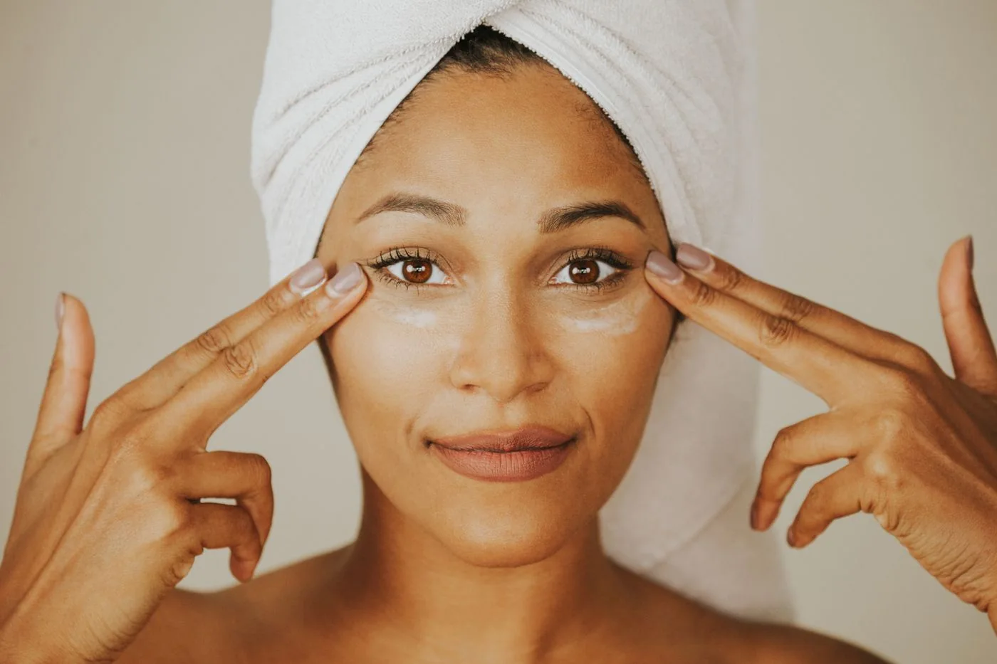 Woman with a towel around her hair applying facial cream