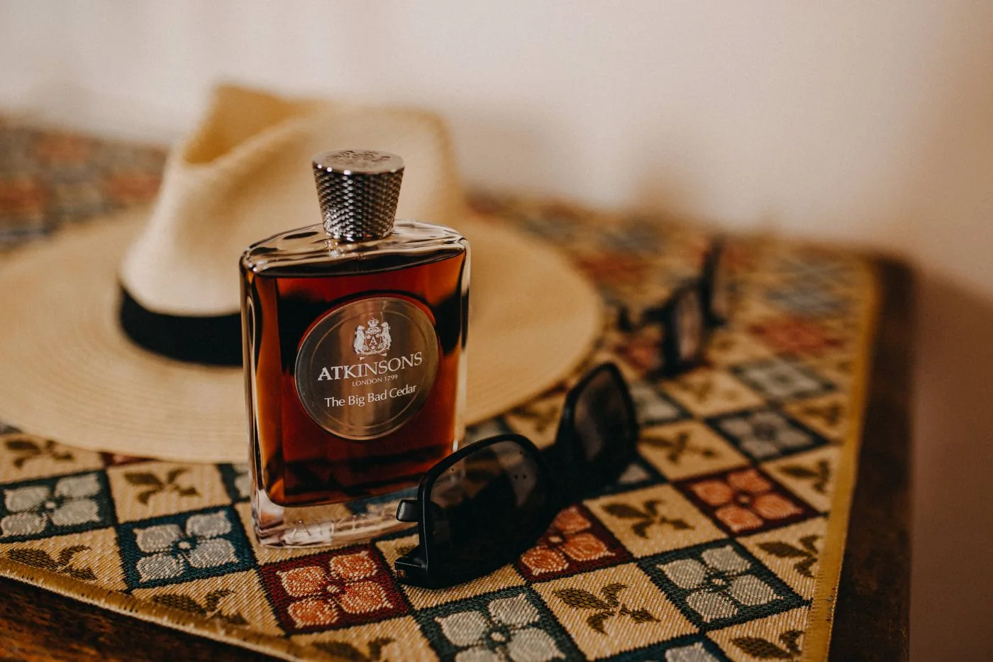 Perfume, a hat and sunglasses arranged on a table