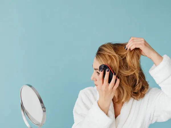 Woman using a small tabletop mirror to comb her hair